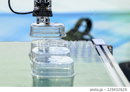 Close up scene material handling process the food container by robotic system from injection machine. Close up scene material handling process the food container by robotic system from injection machine. 129432629
