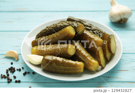 Marinated pickled cucumber with garlic on blue background. Marinated pickled cucumber with garlic on blue background. 129432827