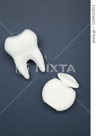 Healthy dental equipment tools for dental care. Plastic tooth with dental floss on dark blue Healthy dental equipment tools for dental care. Plastic tooth with dental floss on dark blue 129432851