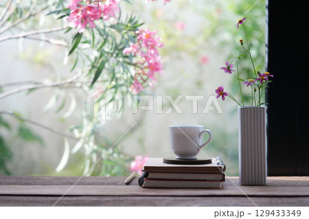 White ceramic coffee cup and delicate pink flowers in a white vase with pink flowers background 129433349