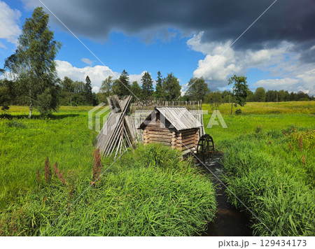 watermill on a stream among thick green grass 129434173