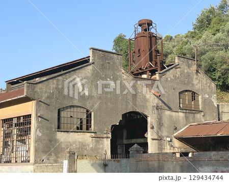 Buildings of old factory. Ruins and rusty structures. Old dilapidated building and nature. 129434744