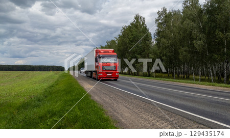 Red Truck Driving on Highway Through Forest Landscape and Field Red Truck Driving on Highway Through Forest Landscape and Field 129435174