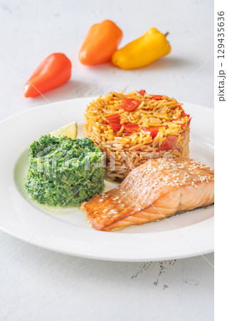 Elegant plated salmon with rice pilaf and creamy spinach on white round plate Elegant plated salmon with rice pilaf and creamy spinach on white round plate 129435636