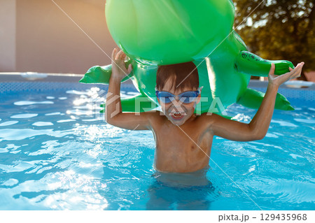 Smiling boy in swimming pool with inflatable toy in summer 129435968