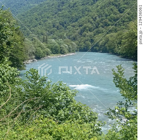 A serene river valley landscape in a natural style, in vibrant green and blue colors, representing pristine nature and tranquility, with copy space A serene river valley landscape in a natural style, in vibrant green and blue colors, representing pristine nature and tranquility, with copy space 129436061