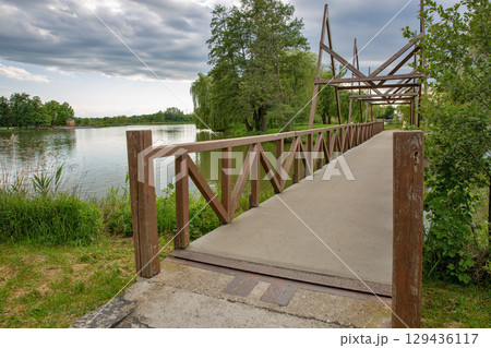 Wooden footbridge over Boating lake in park. Nagykanizsa, Hungary. Wooden footbridge over Boating lake in park. Nagykanizsa, Hungary. 129436117