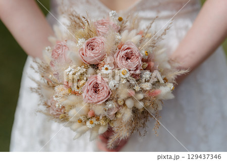 Elegant wedding bouquet with blush roses, wildflowers, and dried grasses in natural tones. Ideal stock image for bridal catalogs, wedding planners, and event promotions. Elegant wedding bouquet with blush roses, wildflowers, and dried grasses in natural tones. Ideal stock image for bridal catalogs, wedding planners, and event promotions. 129437346