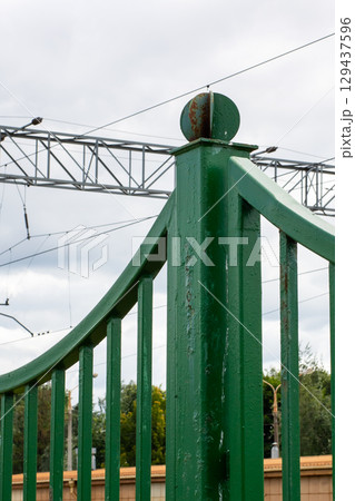 A green fence with a metallic structure stands in the background 129437596
