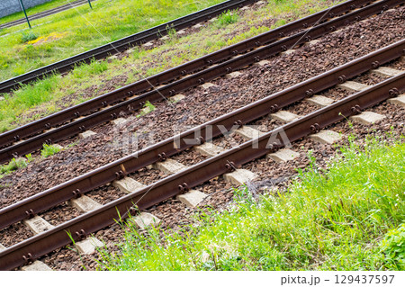 Closeup of a worn train track with grass growing on it Closeup of a worn train track with grass growing on it 129437597