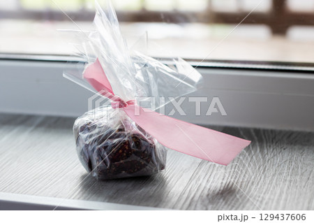 A deliciously wrapped chocolate piece with a pink ribbon A deliciously wrapped chocolate piece with a pink ribbon 129437606