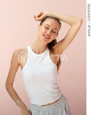 Young woman listening to music, smiling with eyes closed 129439388