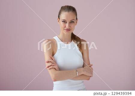 Woman in white athletic tank on pink backdrop Woman in white athletic tank on pink backdrop 129439394