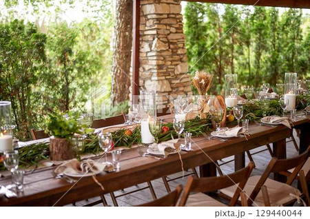 Banquet decoration in a simple rustic style with grass, greenery, simple objects and fabrics. Wedding table setting for guests 129440044