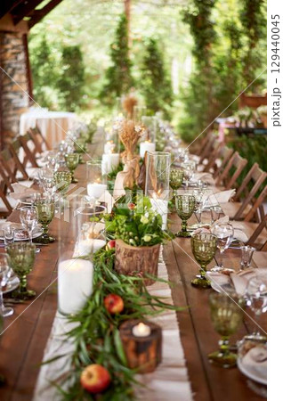 Banquet decoration in a simple rustic style with grass, greenery, simple objects and fabrics. Wedding table setting for guests 129440045