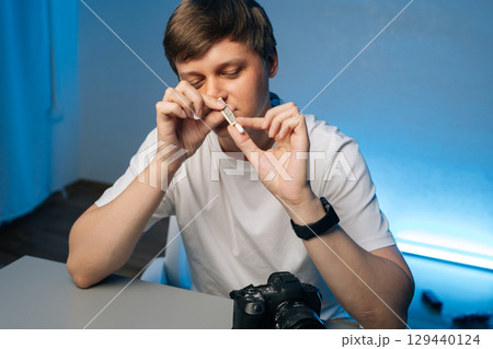 Photographer preparing illegal substance using rolled currency, sitting at workspace near camera, revealing personal struggle with drug dependency. Concept of addiction and substance abuse. 129440124