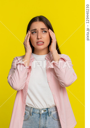 Woman sighing holding hand on head showing painful expression suffering from headache discomfort Woman sighing holding hand on head showing painful expression suffering from headache discomfort 129440230