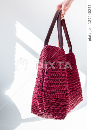 Female hand holding fashionable red woven bag. Fashion and luxury accessories. Vertical photo. High quality photo 129440245