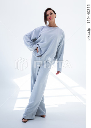 Young woman in gray sweatshirt and pants on white background. Studio photography. Vertical photo. High quality photo 129440256