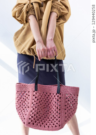 Female hand holding fashionable pink woven bag. Fashion and luxury accessories. Vertical photo. High quality photo Female hand holding fashionable pink woven bag. Fashion and luxury accessories. Vertical photo. High quality photo 129440258