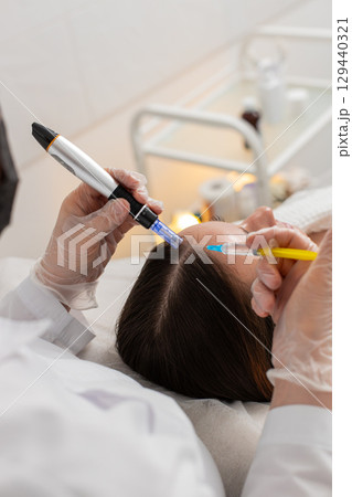 Woman receives microneedling and injections for hair growth scalp therapy in trichology clinic Woman receives microneedling and injections for hair growth scalp therapy in trichology clinic 129440321