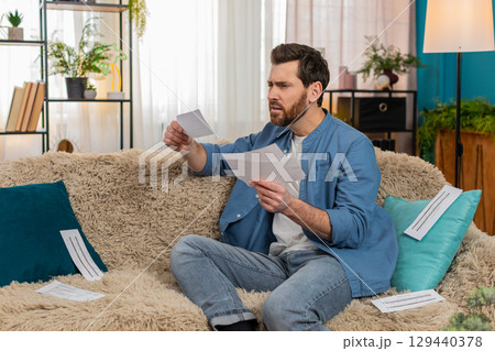 Man throwing home utility bills on sofa, desperate about financial debt, frustration 129440378