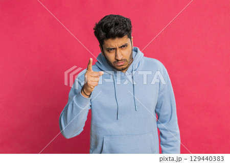 Displeased young Indian man gesturing hands with irritation and displeasure against red background Displeased young Indian man gesturing hands with irritation and displeasure against red background 129440383