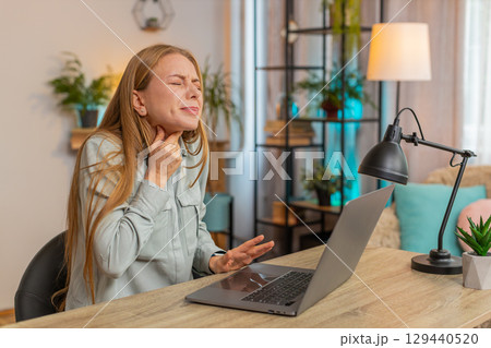 Upset mature Caucasian woman freelancer having sore throat while sitting at home office table desk Upset mature Caucasian woman freelancer having sore throat while sitting at home office table desk 129440520