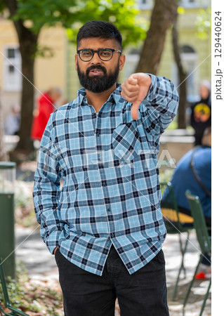 Upset Indian man showing thumbs down sign, disapproval, dissatisfied bad work, mistake in city Upset Indian man showing thumbs down sign, disapproval, dissatisfied bad work, mistake in city 129440624