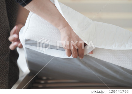 Adjusting a mattress cover on a bed during the morning Adjusting a mattress cover on a bed during the morning 129441793