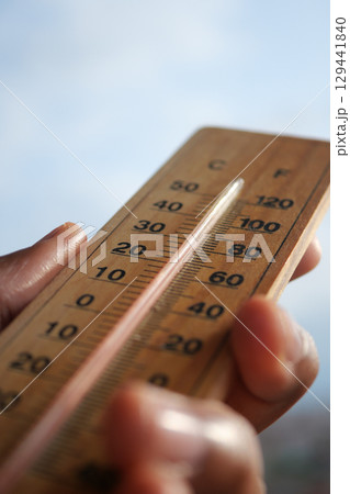 Measuring temperature with a wooden thermometer in hand 129441840