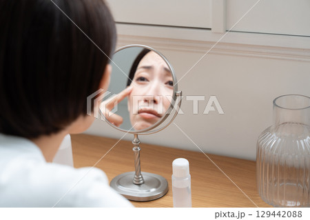 鏡を覗き込み肌の悩み 129442088