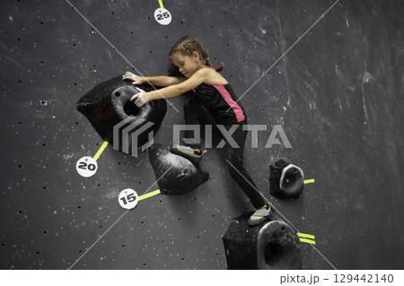 Determined girl climbing artificial wall at 129442140