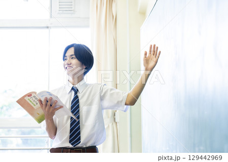 黒板の前で発表する男子高校生 129442969