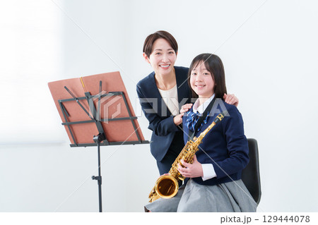 サックスを持つ女子生徒と先生のポートレート サックスを持つ女子生徒と先生のポートレート 129444078