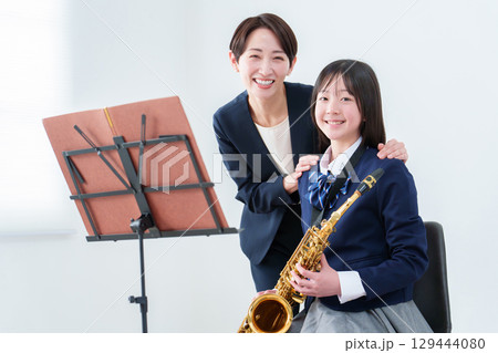 サックスを持つ女子生徒と先生のポートレート 129444080