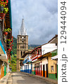 The Neo-Gothic Basilica of the Immaculate Conception rises above a colorful colonial street in the picturesque mountain town of Jardin, Colombia 129444094