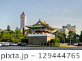 East Gate, a traditional Chinese-style gate tower with green tiles and ornate architecture stands at a roundabout in central Taipei, Taiwan, surrounded by palm trees and urban buildings under a clear 129444765