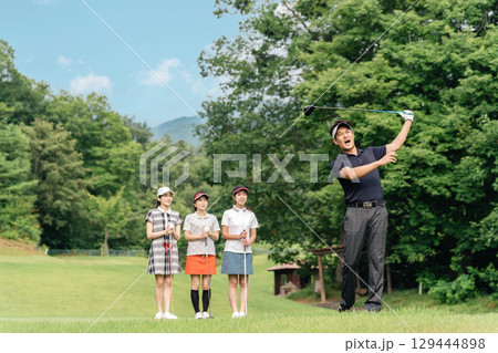 ゴルフ場でティーショットを打つ男性ゴルファーとスイングを見る同伴のゴルファー（ミスショット） 129444898