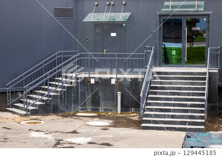 A tall black building features stairs that lead up to its entrance A tall black building features stairs that lead up to its entrance 129445185