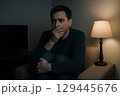 暗い部屋でテレビを見る若い男性 129445676
