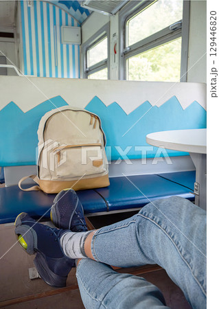 Person traveling by train with backpack on seat. Person traveling by train with backpack on seat. 129446820
