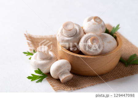 White Button mushroom or Champignon mushroom (Agaricus bisporus) in wooden bowl on white background 129447098
