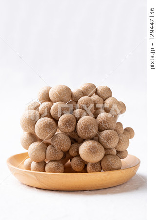 Fresh brown Shimeji mushroom on wooden plate with white background 129447136