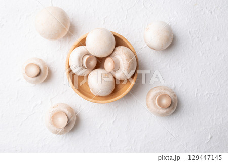 Top view of fresh white Champignon mushroom (botton mushroom) in wooden bowl on white background 129447145