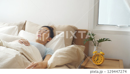 Asian women sleep wake up in white cozy bedroom happy time morning sunrise. Beautiful chinese use hand stop time alarm clock. Happy person lifestyle wake up in morning wellbeing relax sleepy napping 129447274