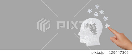 A hand interacts with a puzzle head symbolizing thoughts and ideas A hand interacts with a puzzle head symbolizing thoughts and ideas 129447303