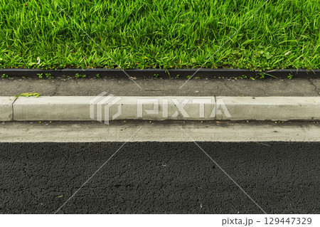 縁石に沿って生い茂る青々とした草と道路 129447329
