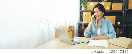 Banner Online seller Close up hands Young asian woman typing laptop keyboard checking online order on stock delivery package. Asian woman startup small business at home office with copy space 129447333