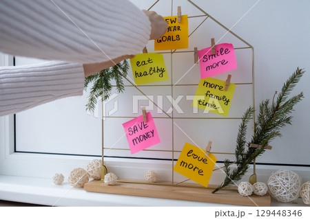 Woman creating dream board promises and aims. Preparation for new year new life new me. Visualizing wish list for 2025. Dreams plan action resolutions for coming year. Inspirational self improvement 129448346